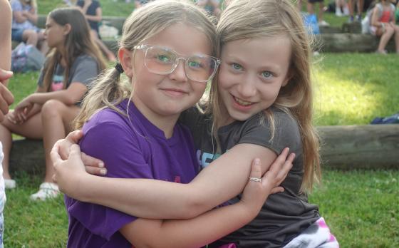 Two campers sitting at flag pole at YMCA Camp Bay View
