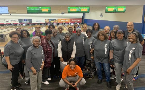 a group of members from the thurston road ymca neighborhood center gathered together at a bowling alley with a few staff members