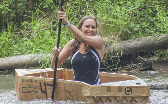 a camp counselor rowing a cardboard boat