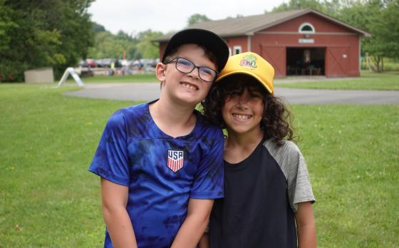 two kids standing in front of a shelter and smiling at the camera at YMCA Camp Eastside