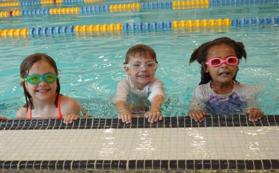 three kids wearing googles in the pool at the Eastside Family YMCA