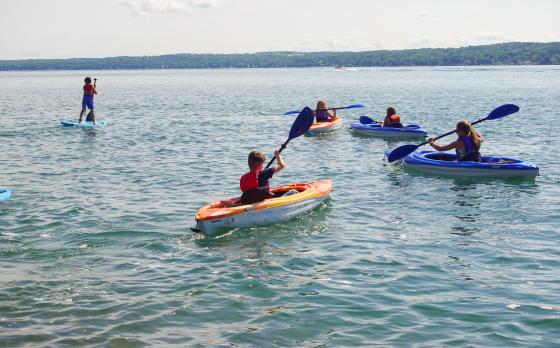 a group of campers on Canandaigua Lake in kayaks and on paddleboards