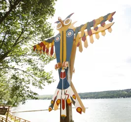 Photo of thunderbird totem at Camp Cory with lake in the background