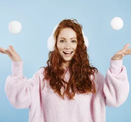 woman throwing snowballs in the air and smiling at the camera