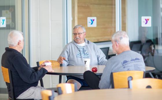 A group of older men sitting at a table with coffee at the Westside Family YMCA