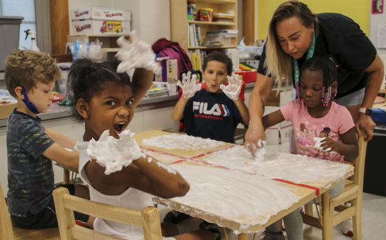 a group of kids at a table doing a craft with shaving cream