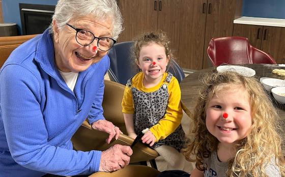 an active older adult member and two preschool children with red noses for the holiday season