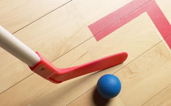 a plastic floor hockey stick with a ball on a gymnasium floor
