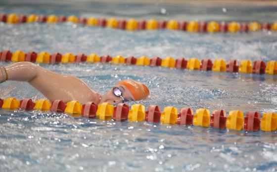 a person in an orange swim cap and goggles swimming laps