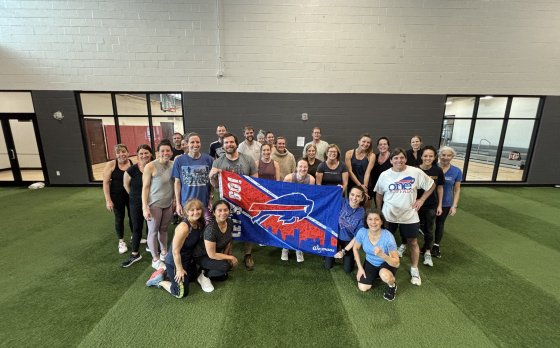 a group of adults standing behind a buffalo bills flag