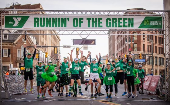 People jumping and celebrating a the finish line at Runnin' of the Green race.