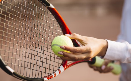 person holding tennis ball and racket