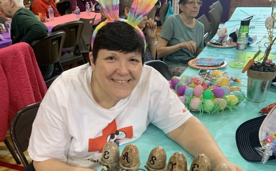 member wearing bunny ears with easter egg craft