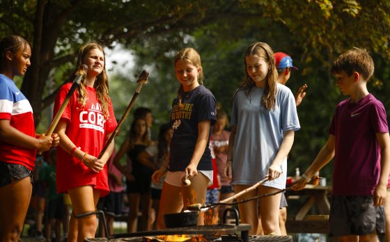Campers roasting s'mores over campfire.