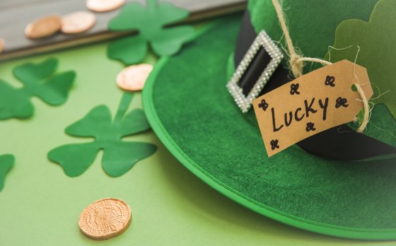 Saint Patrick's hat with tag near coins and decorative clovers
