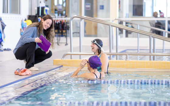 swim instructor talking to students poolside