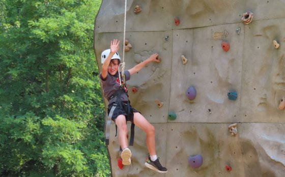 Kid on rock wall waving to the camera 