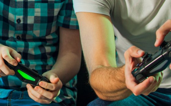father and child playing video games together, holding controllers