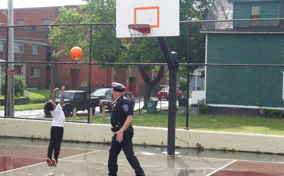 a police officer and a child playing basketball together on a outdoor basketball court