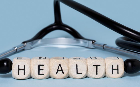 stethoscope laying flat with with block letters spelling out "health" in between the ear pieces