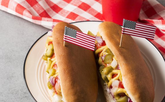 hot dogs with American flag toothpicks on a picnic blanket 