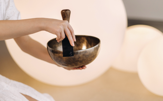 instructor using sound bath singing bowl with wooden striker