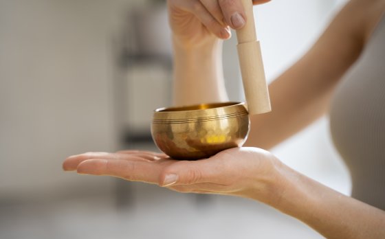 instructor using sound bath singing bowl with wooden striker