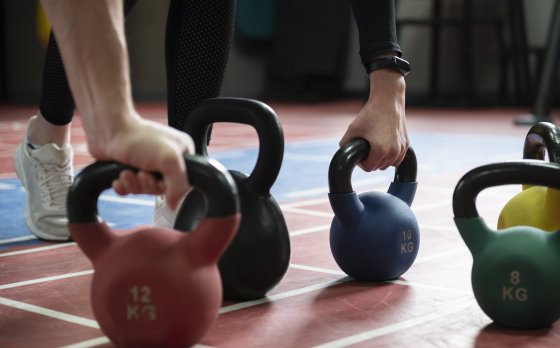 hands grabbing multi colored kettle bells