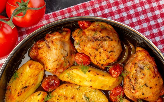 chicken dinner on picnic cloth next to tomatoes