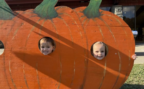 children with their heads in pumpkin cut outs