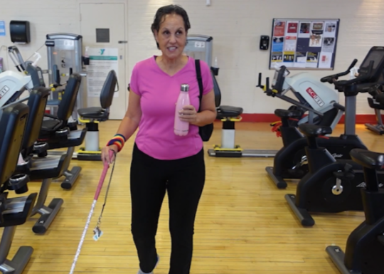 Lea Werner in Wellness Center holding mobility cane and water bottle