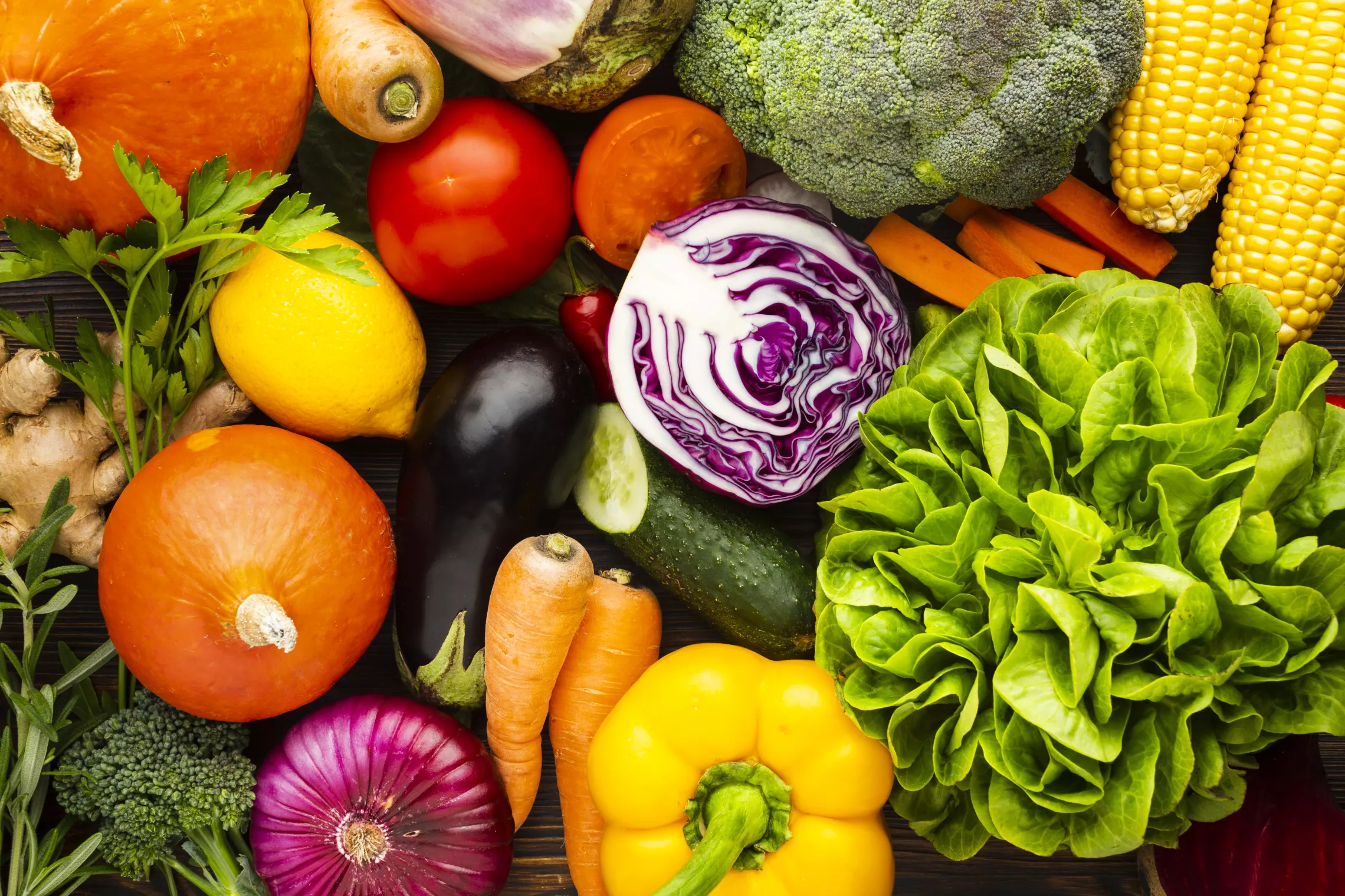 a bunch of vegetables including corn on the cob, broccoli, squash, lettuce, cabbage, bell peppers, onions, eggplant, ginger, carrots