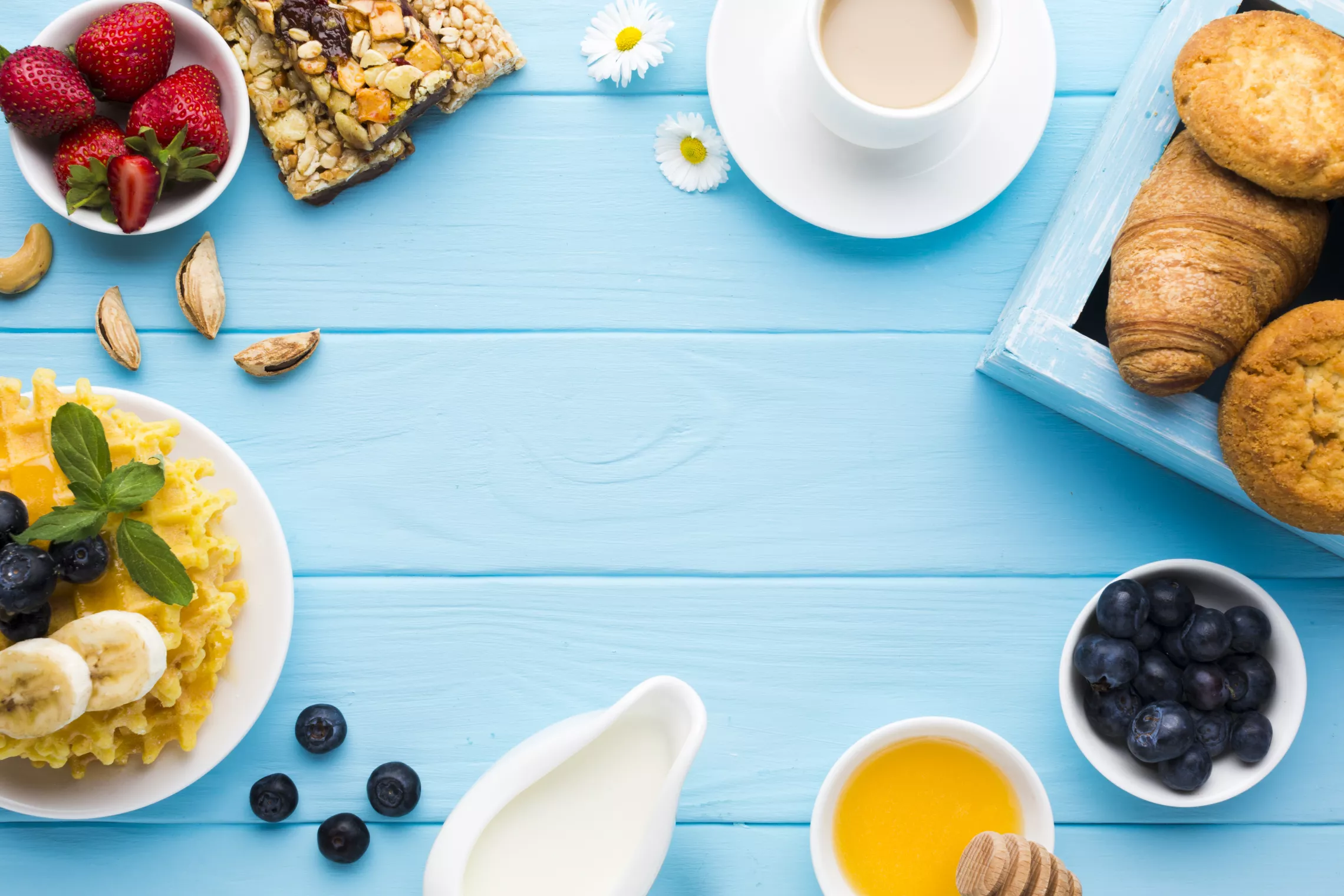a blue table with plates of baked goods, waffles, berries and coffee