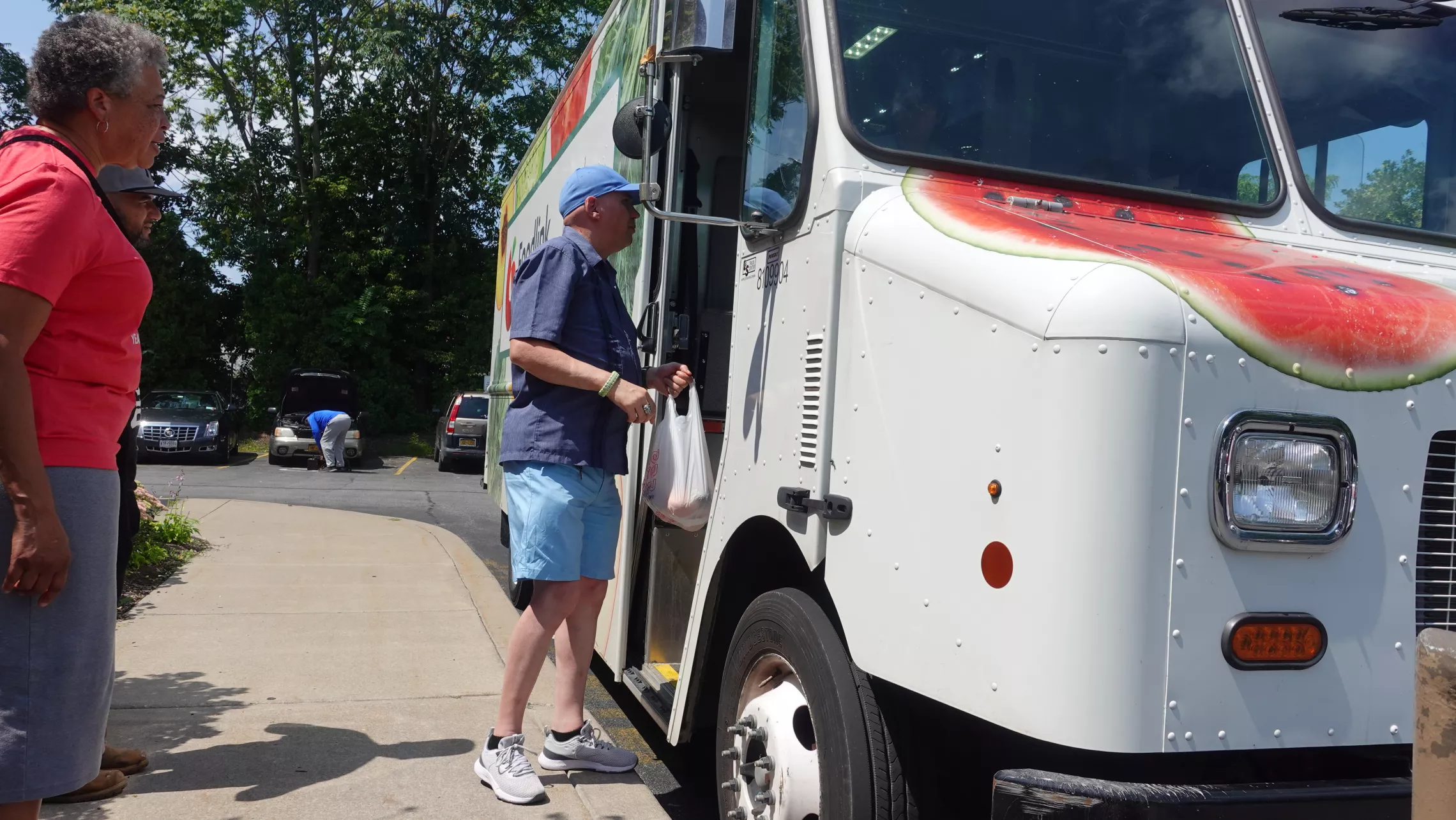 an older man talking to the driver of the Foodlink Curbside Market food truck