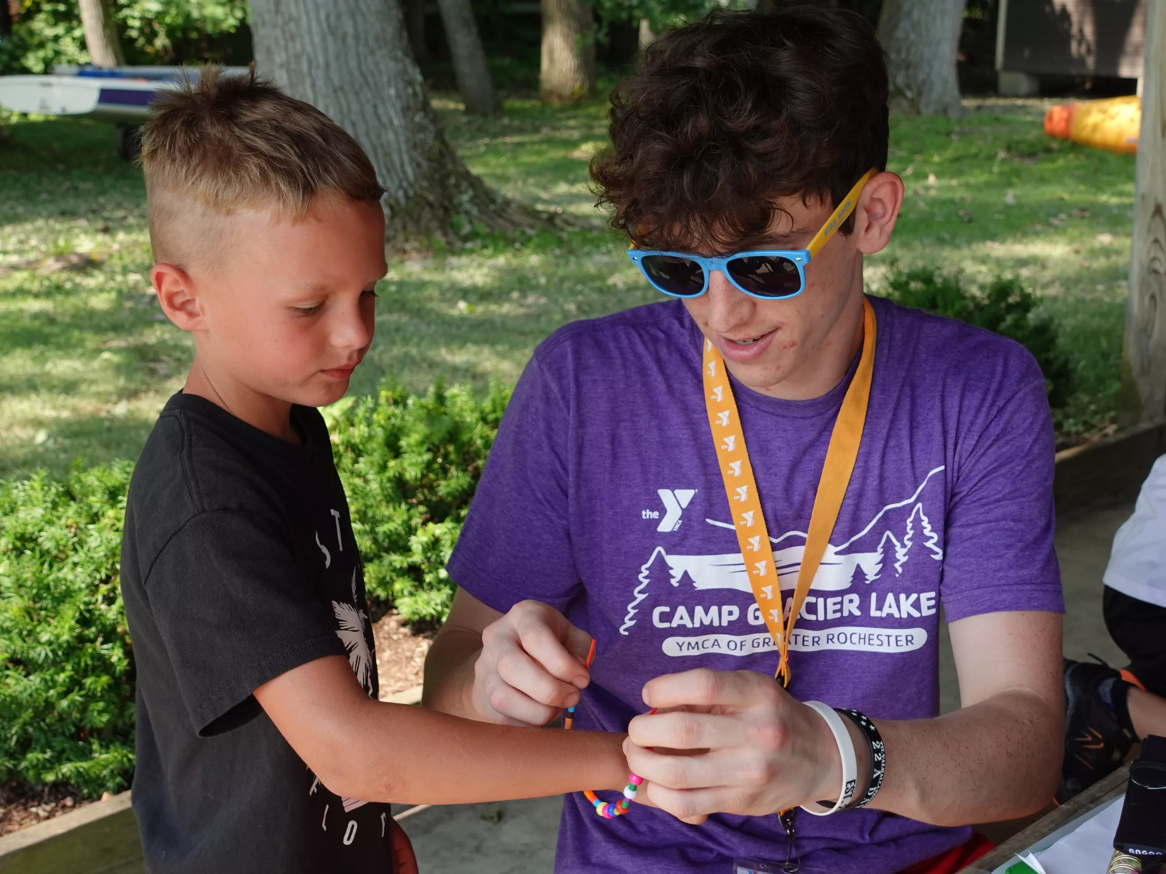 camp glacier lake counselor tying a bracelet on a camper