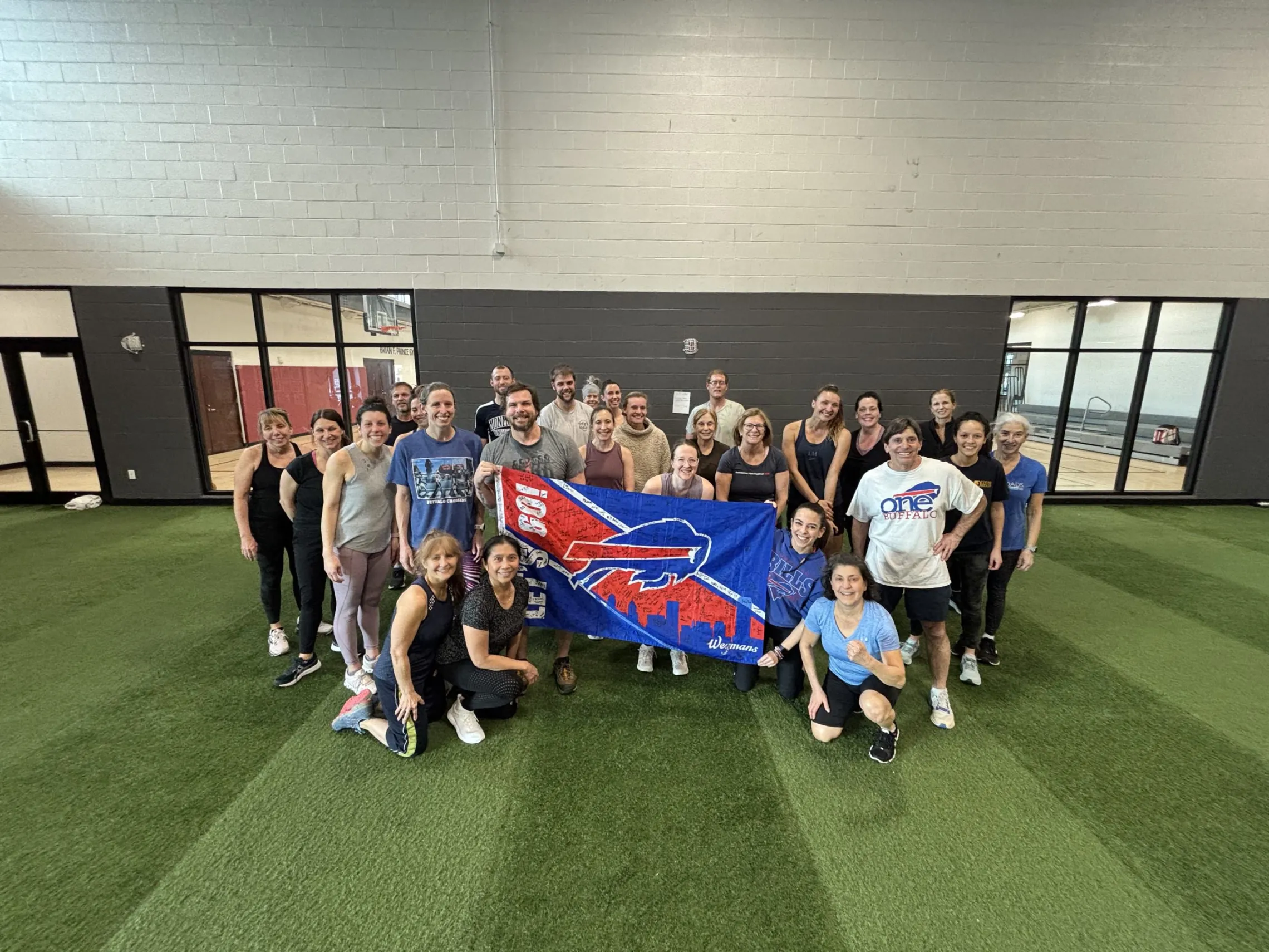 a group of adults standing behind a buffalo bills flag