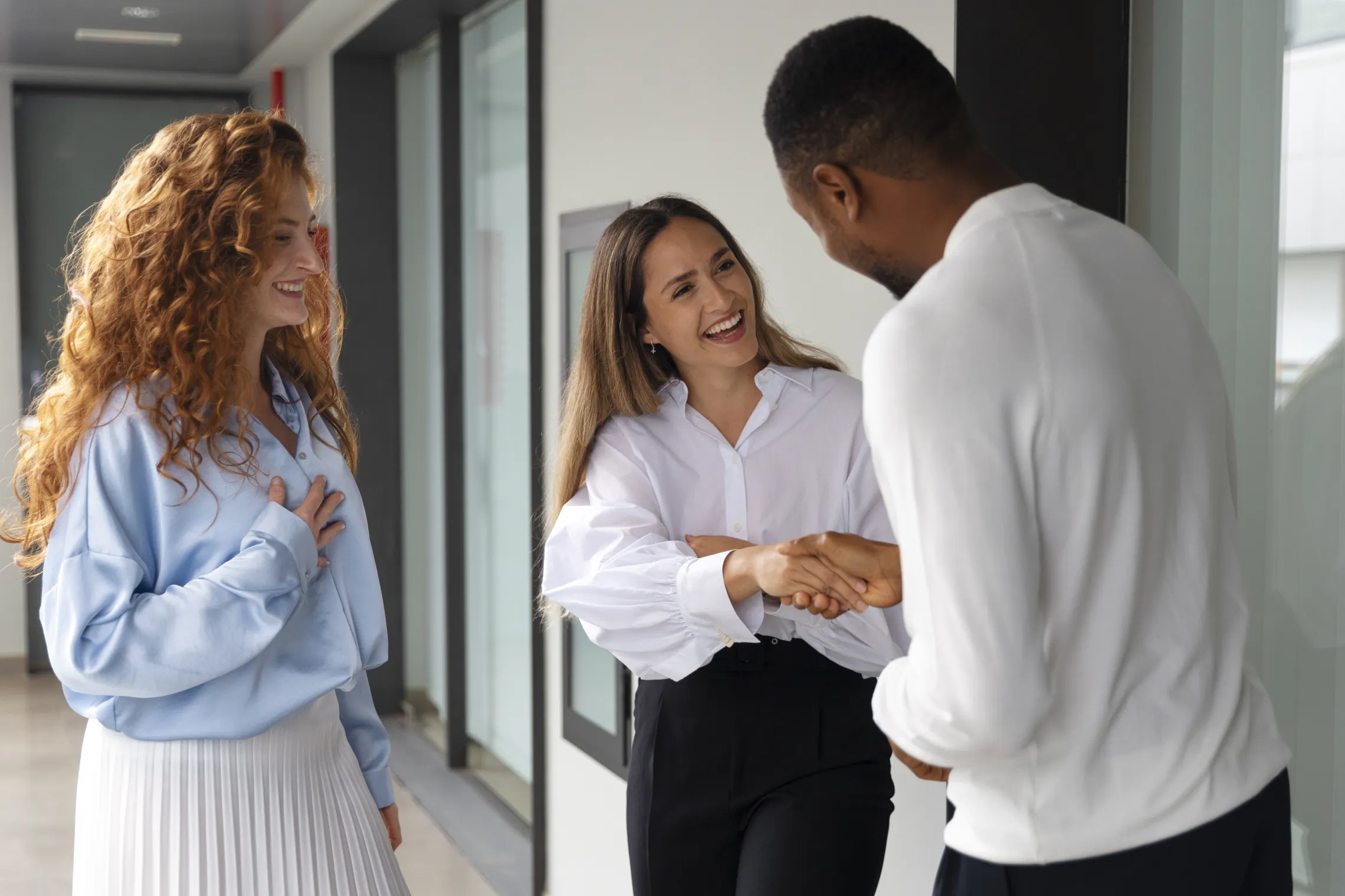 A group of three adults standing together and shaking hands.