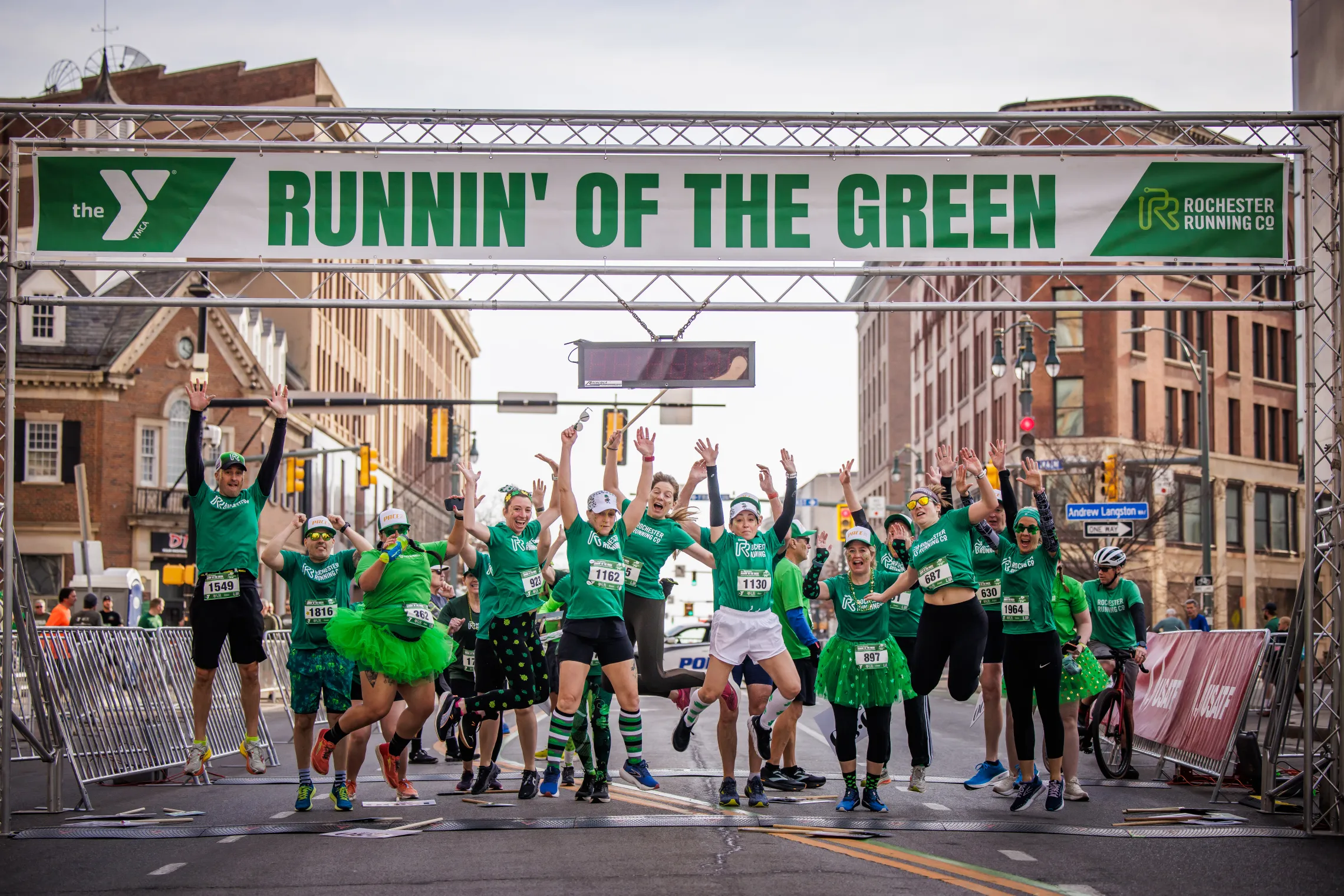 People jumping and celebrating a the finish line at Runnin' of the Green race.