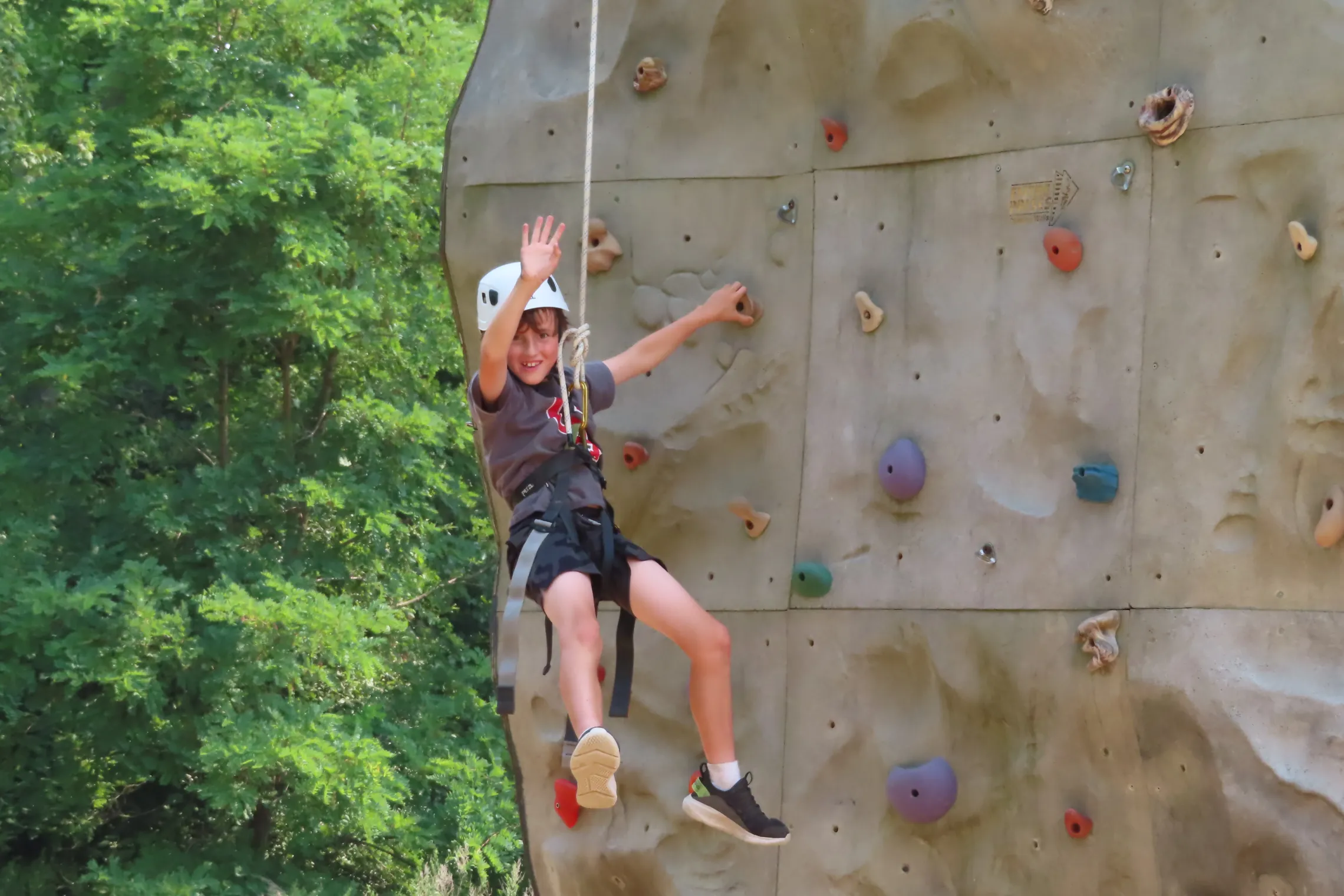 Kid on rock wall waving to the camera