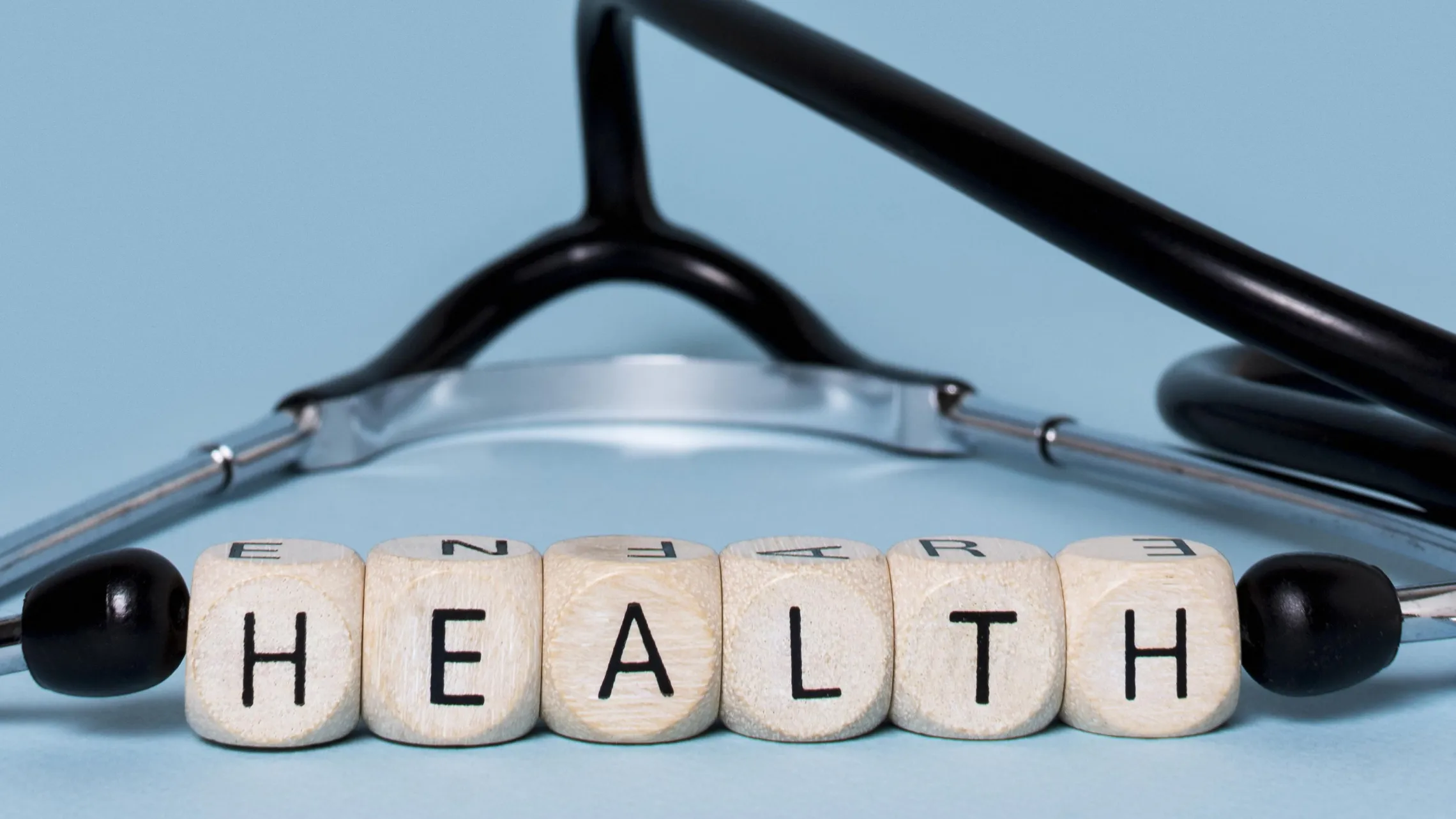 stethoscope laying flat with with block letters spelling out "health" in between the ear pieces