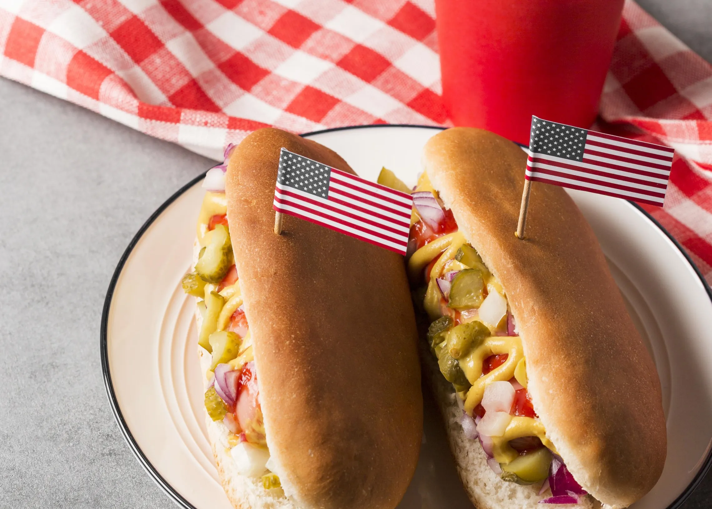 hot dogs with American flag toothpicks on a picnic blanket