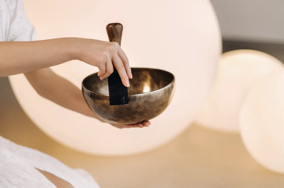 instructor using sound bath singing bowl with wooden striker