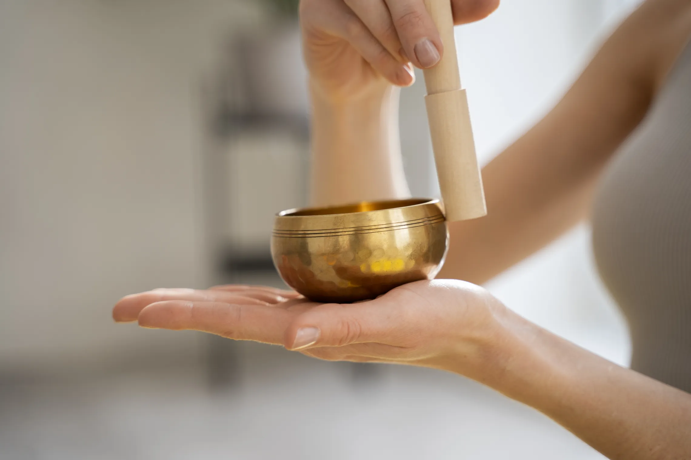 instructor using sound bath singing bowl with wooden striker