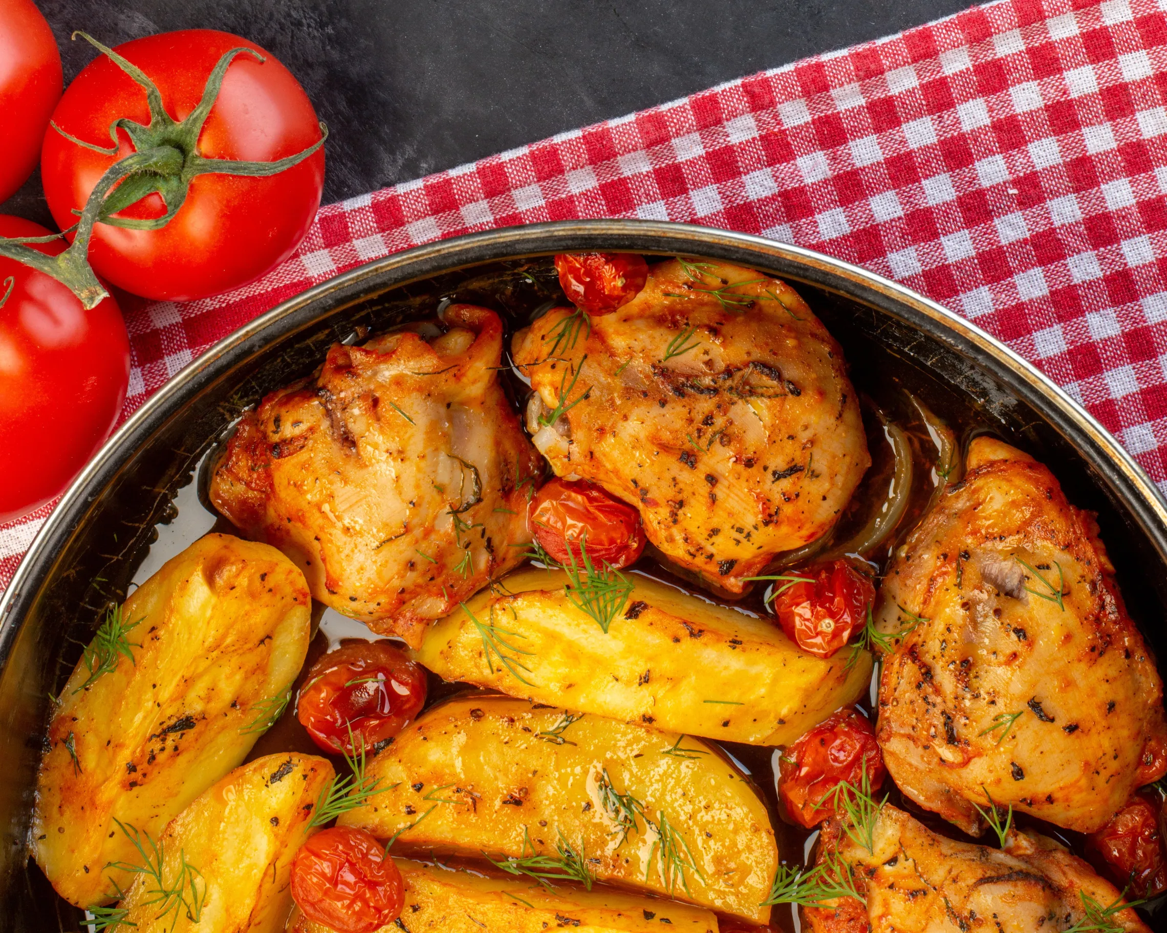 chicken dinner on picnic cloth next to tomatoes
