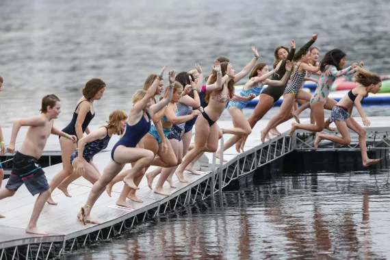 Group of campers jumping off dock into Dart's Lake