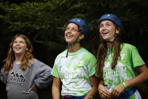 Teen campers in climbing helmets looking up and smiling