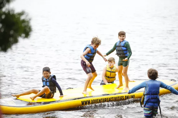 young campers bouncing on inflatable in the lake