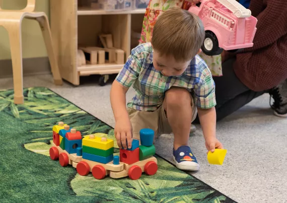 a child playing with a wooden train on the floor