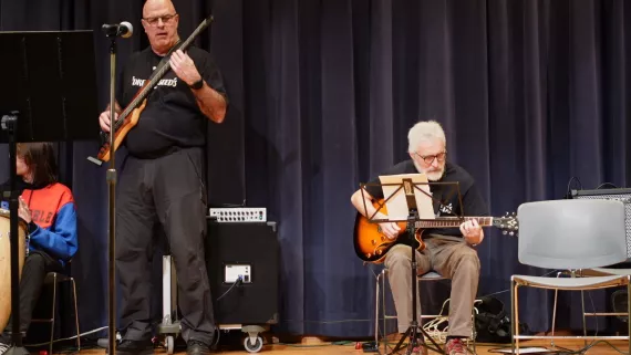 two men playing guitar on a stage