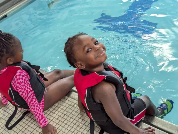 2 children wait on the deck of the pool at the Maplewood Family YMCA as a part of the Summer LEAP program.